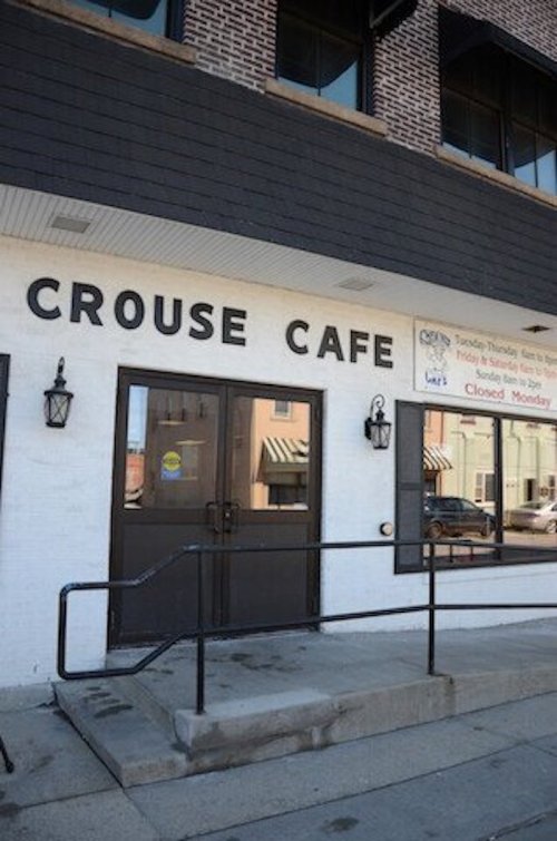 Exterior of Crouse Cafe with a sign indicating hours and a closed notice for Monday. Steps lead to the entrance.