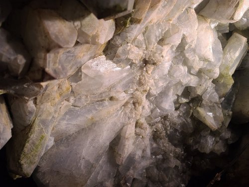 Close-up of crystalline mineral formations with sharp, translucent edges and a shimmering surface.