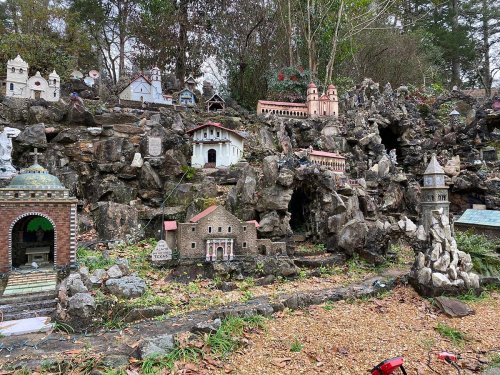 A miniature village scene with various small buildings and structures set among rocks and greenery.