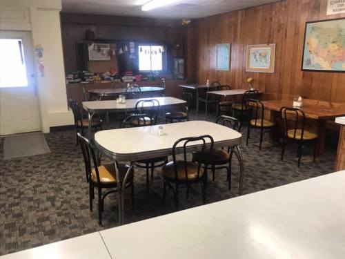 A cozy dining area with several tables and chairs, featuring wooden paneling and a map on the wall.