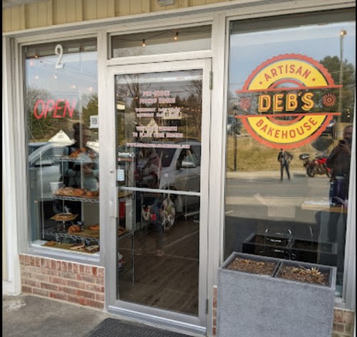 Exterior view of Deb's Artisan Bakehouse with an "Open" sign and display of baked goods in the window.