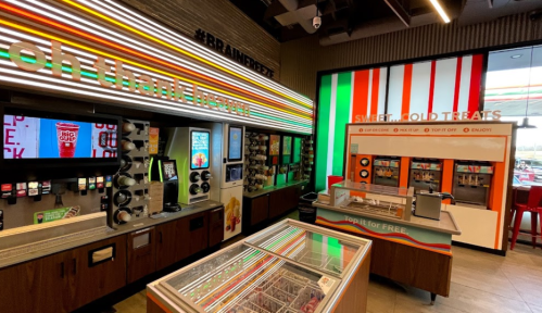 Brightly colored convenience store interior featuring drink dispensers, ice cream machines, and a dessert display.