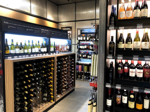 A wine store interior featuring shelves of various wines, including white and red bottles, organized neatly.