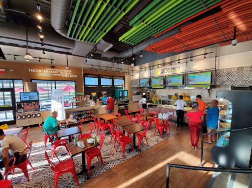 A vibrant restaurant interior with colorful decor, tables, and a counter displaying menu items and drinks.