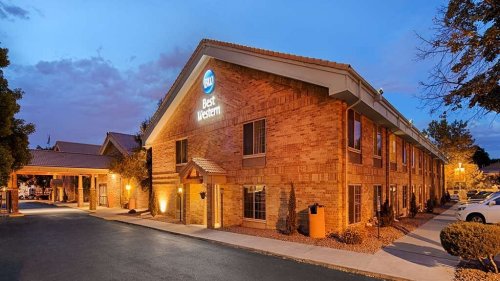 Exterior view of a Best Western hotel at dusk, featuring brick architecture and illuminated signage.
