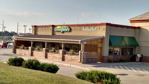 Exterior view of Greenfield's Restaurant, featuring a brick facade and green awnings, set in a parking lot.