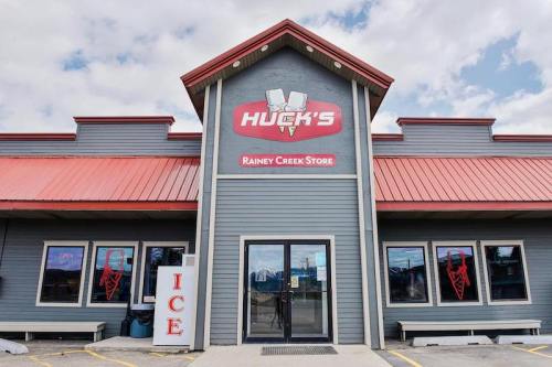 Front view of Huck's Rainey Creek Store, featuring a red roof and large sign, with an ice vending machine outside.