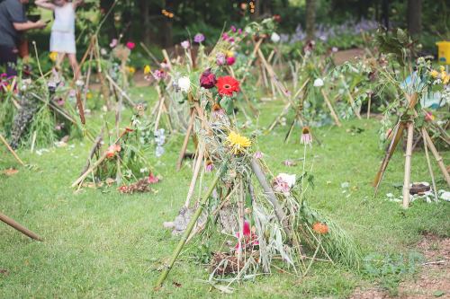 Colorful flower arrangements on wooden structures in a lush green garden setting.