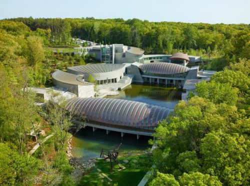 Aerial view of a modern building complex surrounded by lush greenery and water features.