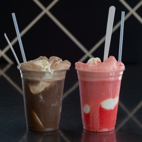 Two cups of colorful ice cream floats, one chocolate and one strawberry, each with a spoon.