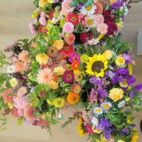 A vibrant arrangement of colorful flowers, including sunflowers, zinnias, and daisies, in various shades and sizes.