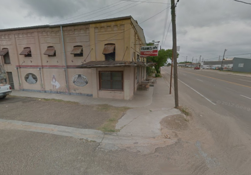 A street view of a building with a sign for "Frank's" and murals on the wall, set against a cloudy sky.
