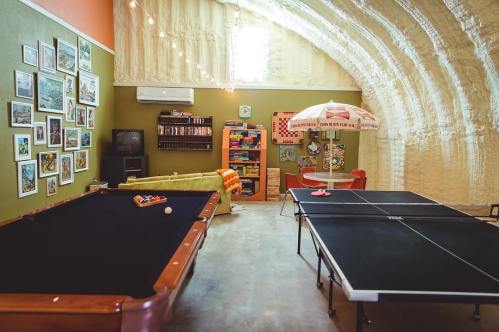A cozy game room featuring a pool table, ping pong table, and colorful decor with framed pictures on the walls.
