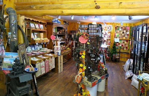 A cozy gift shop filled with various crafts, souvenirs, and decorative items, featuring wooden decor and colorful displays.
