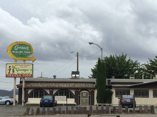 A Mexican restaurant named Guaya's, featuring a sign and a rustic building under a cloudy sky.