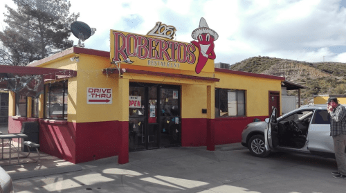 A colorful restaurant exterior with a sign reading "Roberto's" and a drive-thru, set against a hilly backdrop.