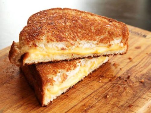 A perfectly toasted grilled cheese sandwich, cut in half, revealing melted cheese between golden-brown bread.