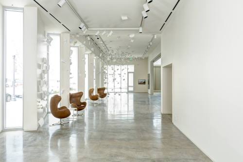 Modern interior with sleek brown chairs, large windows, and a minimalist design featuring scattered paper elements.
