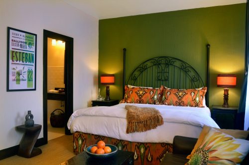 Cozy bedroom featuring a large bed with colorful bedding, decorative lamps, and a vibrant green accent wall.