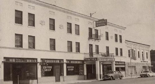 Historic hotel building with a coffee shop, featuring a classic facade and vintage cars parked outside.