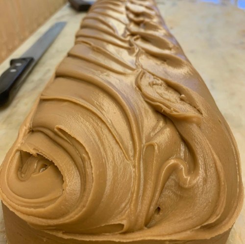Close-up of a smooth, swirled layer of chocolate frosting on a cake, showcasing rich texture and creamy finish.