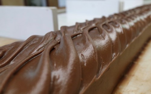 Close-up of smooth, swirled chocolate frosting on a cake, showcasing rich texture and glossy finish.