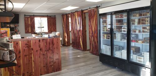Interior of a shop featuring wooden decor, a display fridge, and partitioned areas with natural light.
