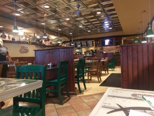 Interior of a casual restaurant with wooden booths, green chairs, and a warm, inviting atmosphere.