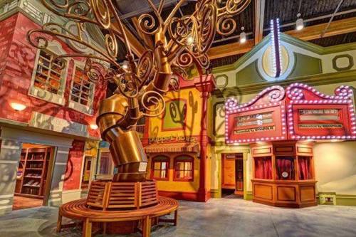 Colorful indoor space featuring a large, whimsical tree sculpture and vibrant buildings with playful designs.