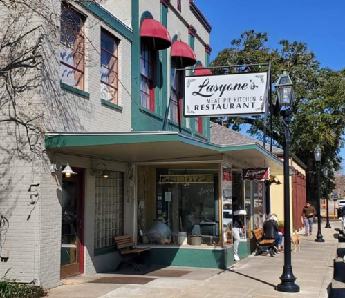 Exterior of Lasoyne's Meat Pie Kitchen & Restaurant, featuring a sign, outdoor seating, and a sunny street scene.