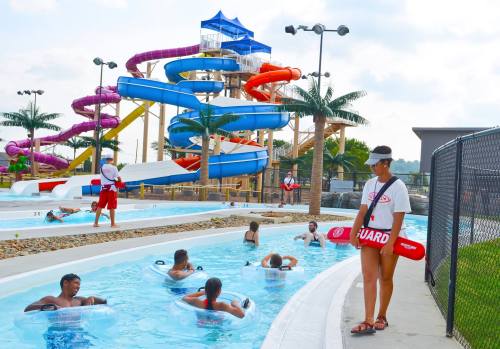 A water park scene with colorful slides, a lifeguard on duty, and guests floating in a lazy river.