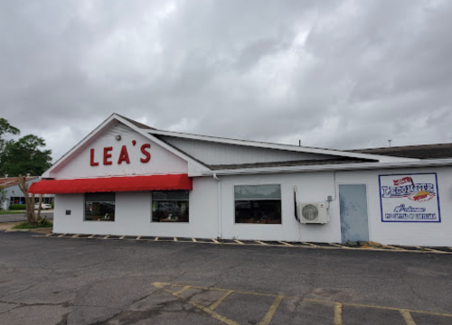 Exterior of Lea's restaurant with a red awning, large windows, and a cloudy sky in the background.
