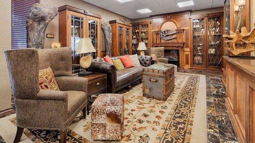 Cozy lounge with plush seating, wooden cabinets, a fireplace, and decorative rugs, creating a warm, inviting atmosphere.