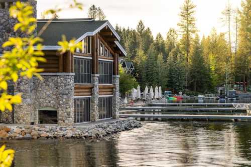 A lakeside cabin with stone walls, surrounded by trees and a dock with boats, reflecting the warm glow of sunset.