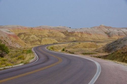 Winding road through colorful, layered hills under a clear sky.
