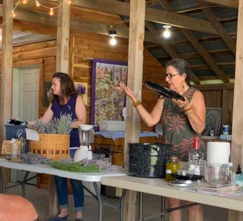 Two women in a rustic setting prepare ingredients at a table, surrounded by kitchen items and decor.