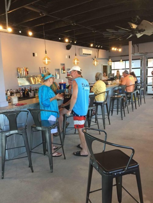 A lively bar scene with patrons chatting at the counter, surrounded by modern decor and warm lighting.