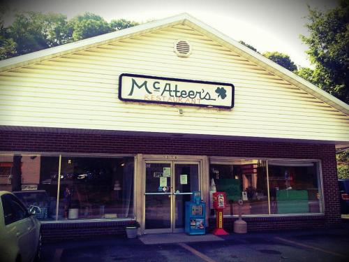 Exterior of McAteer's Restaurant, featuring a sign and large windows, with a parking area in front.