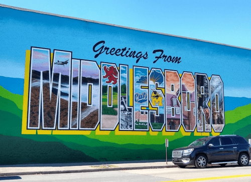 Colorful mural reading "Greetings From Middlesboro" with images representing the town's landmarks and culture.