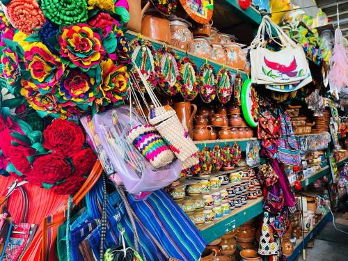 Colorful market display featuring handmade crafts, vibrant flowers, woven bags, and traditional pottery.