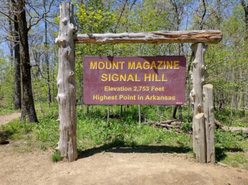 Sign for Mount Magazine Signal Hill, elevation 2,753 feet, the highest point in Arkansas, surrounded by greenery.