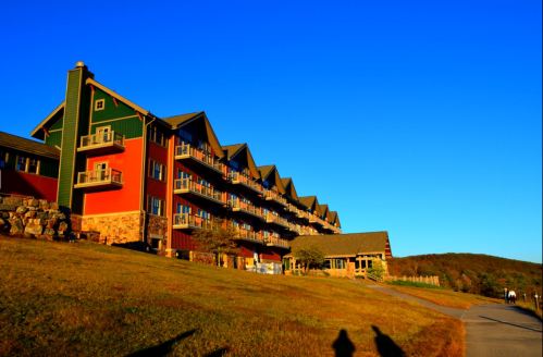 A colorful lodge with multiple balconies, set against a clear blue sky and grassy landscape.