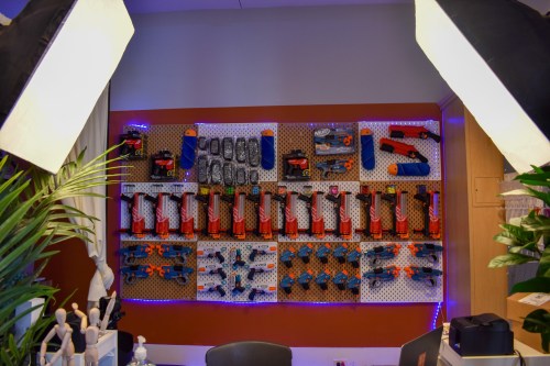 A wall display featuring various tools and equipment, illuminated with blue lights, surrounded by plants and studio lighting.