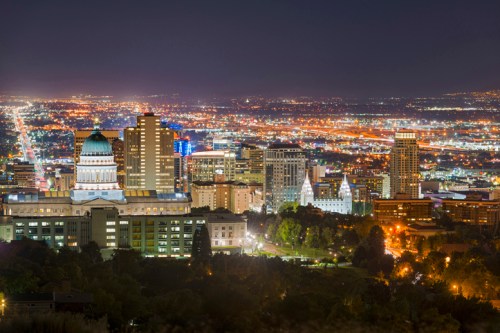 A nighttime cityscape featuring illuminated buildings and streets, with a prominent dome structure in the foreground.