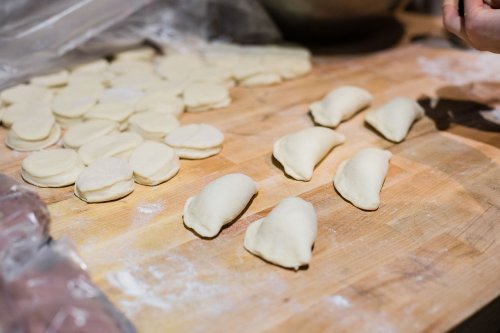 Dough pieces and shaped dumplings on a wooden surface, with flour scattered around.