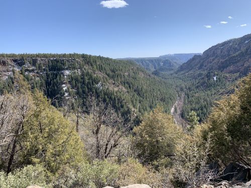 A scenic view of a lush green valley surrounded by mountains under a clear blue sky.