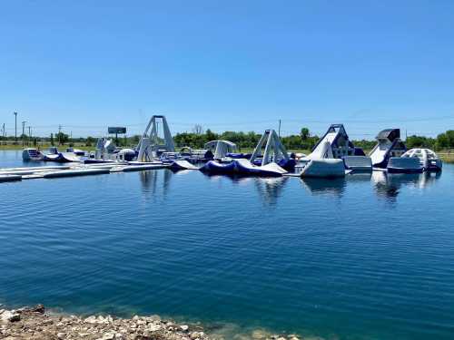 A water park featuring inflatable obstacle courses on a calm lake under a clear blue sky.