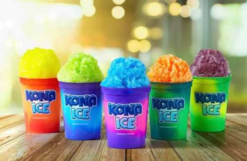 Five colorful cups of Kona Ice with vibrant shaved ice, arranged on a wooden table with a blurred background.