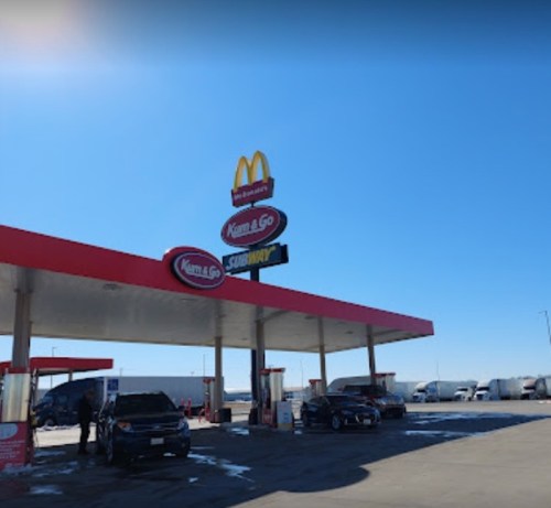 A gas station featuring a McDonald's and Subway sign under a clear blue sky.