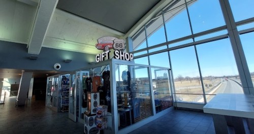 A gift shop with a Route 66 theme, featuring merchandise and large windows overlooking a highway.